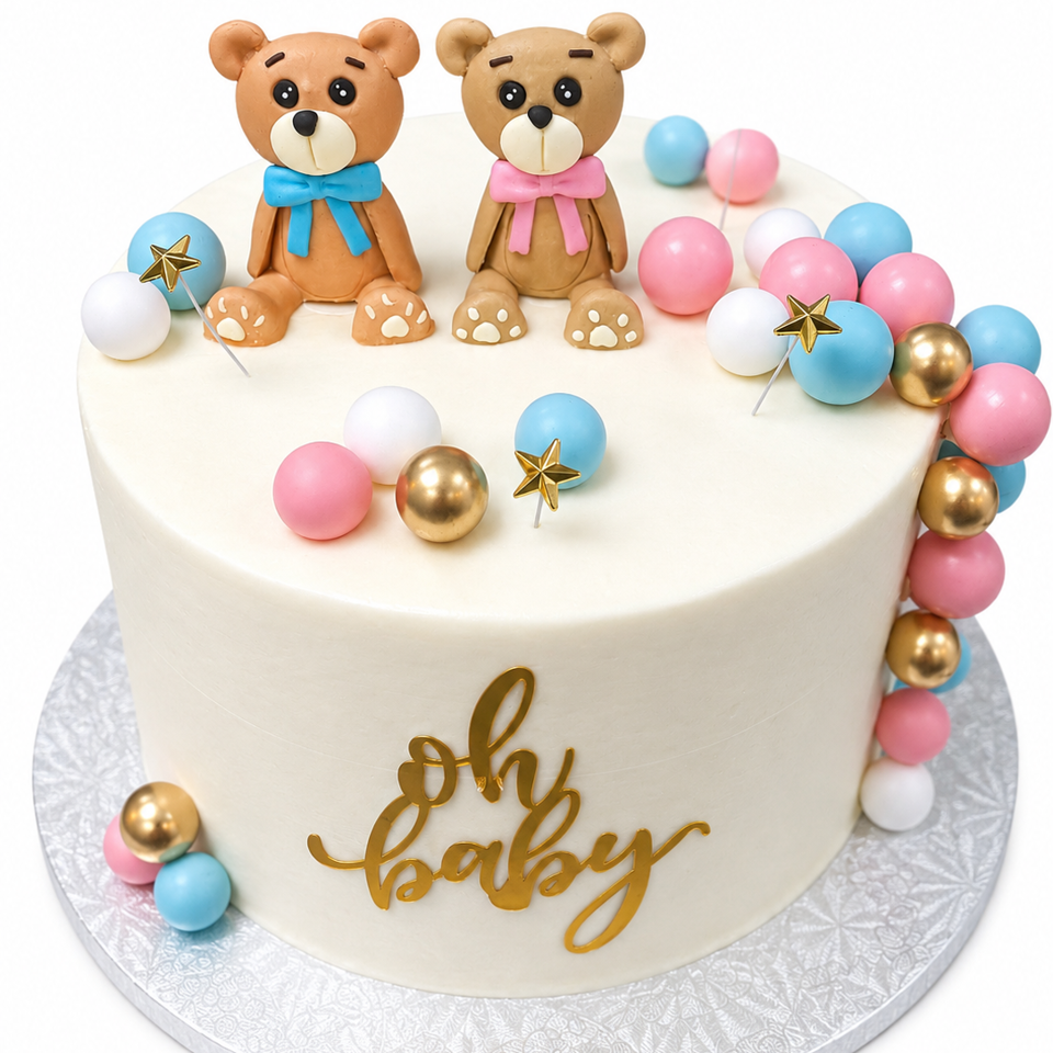 White baby shower cake decorated with two teddy bears, colorful balls, gold stars, and gold “oh baby” lettering.