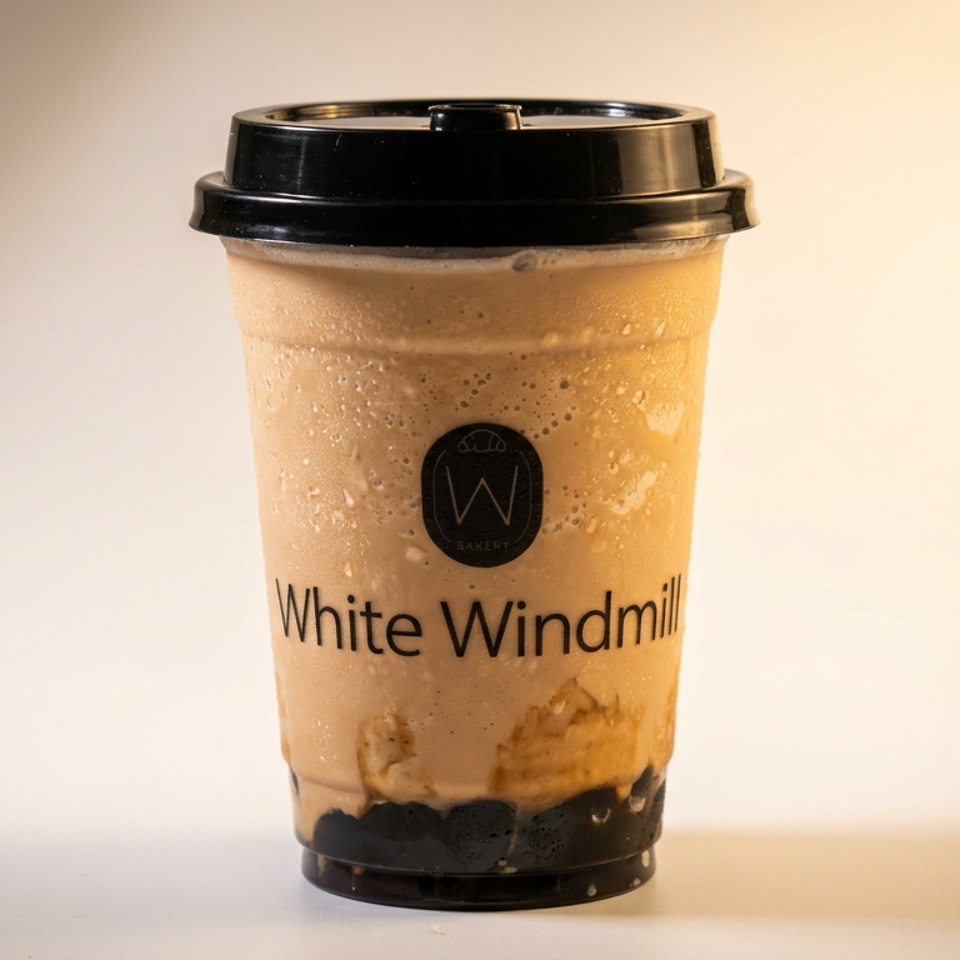 White Windmill Bakery branded blended drink with boba in a clear plastic cup.