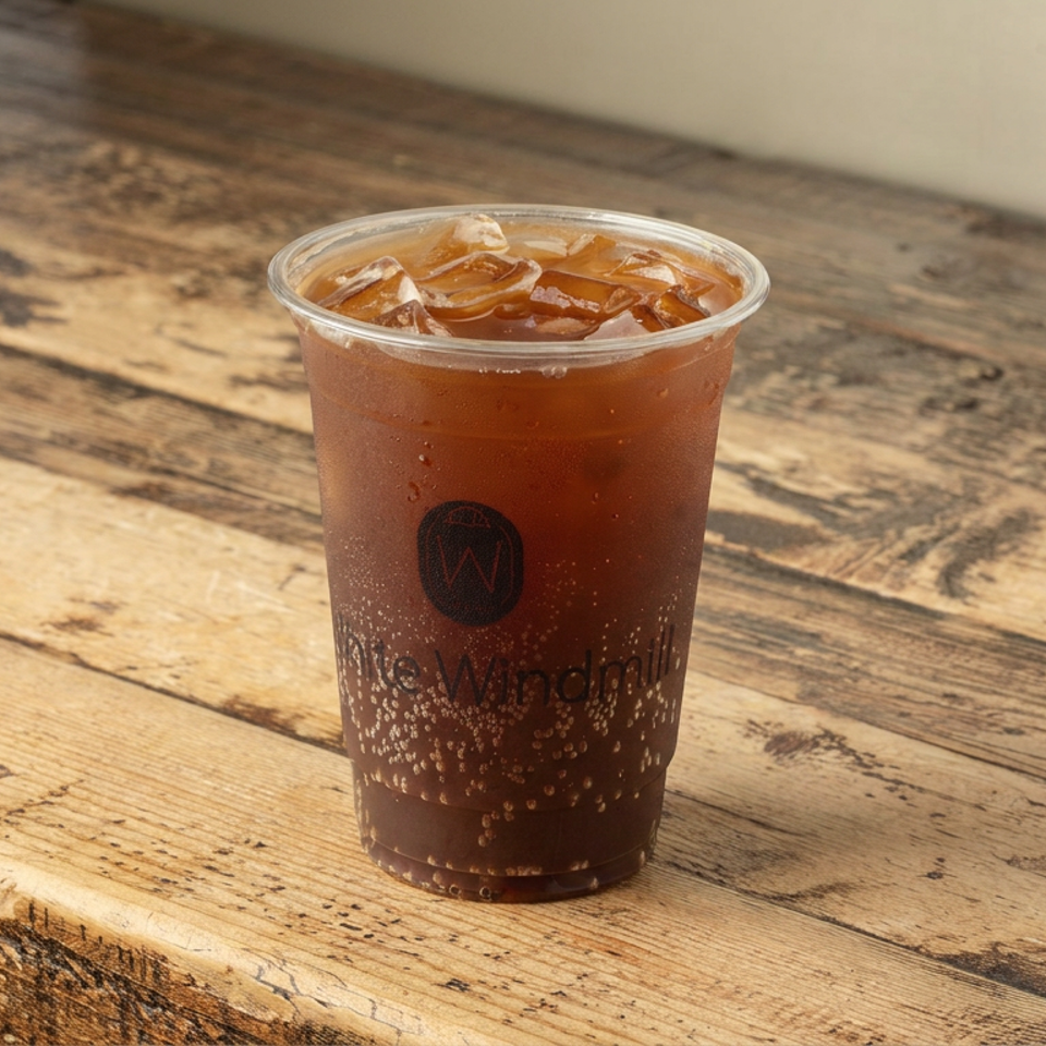 Iced tea in a branded plastic cup sits on a rustic wooden table.