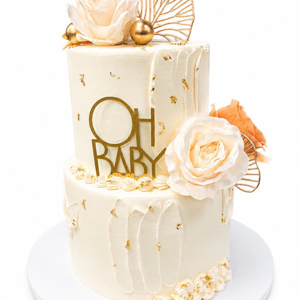 Elegant two-tier ivory cake decorated with white roses, gold accents, fan ornaments, and an “OH BABY” topper.
